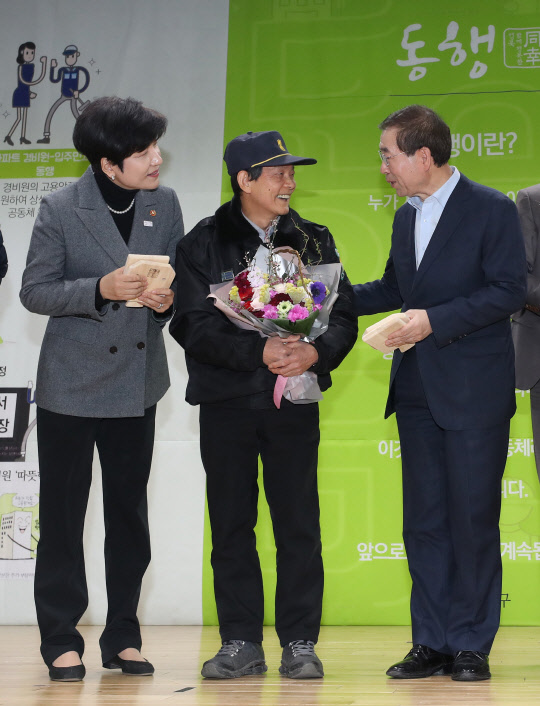경비원에 꽃다발 전달하는 박원순 시장-김영주 장관 5일 오후 서울 성북구청에서 열린 아파트 경비노동자 고용안정 설명회에 박원순 서울시장(오른쪽부터), 동아에코빌 아파트 경비원 김서현씨, 김영주 고용노동부 장관이 꽃다발 증정식을 갖고 있다. 2018.2.5